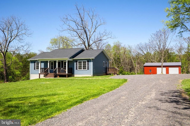 view of front of house with covered porch, driveway, an outbuilding, a detached garage, and a front lawn