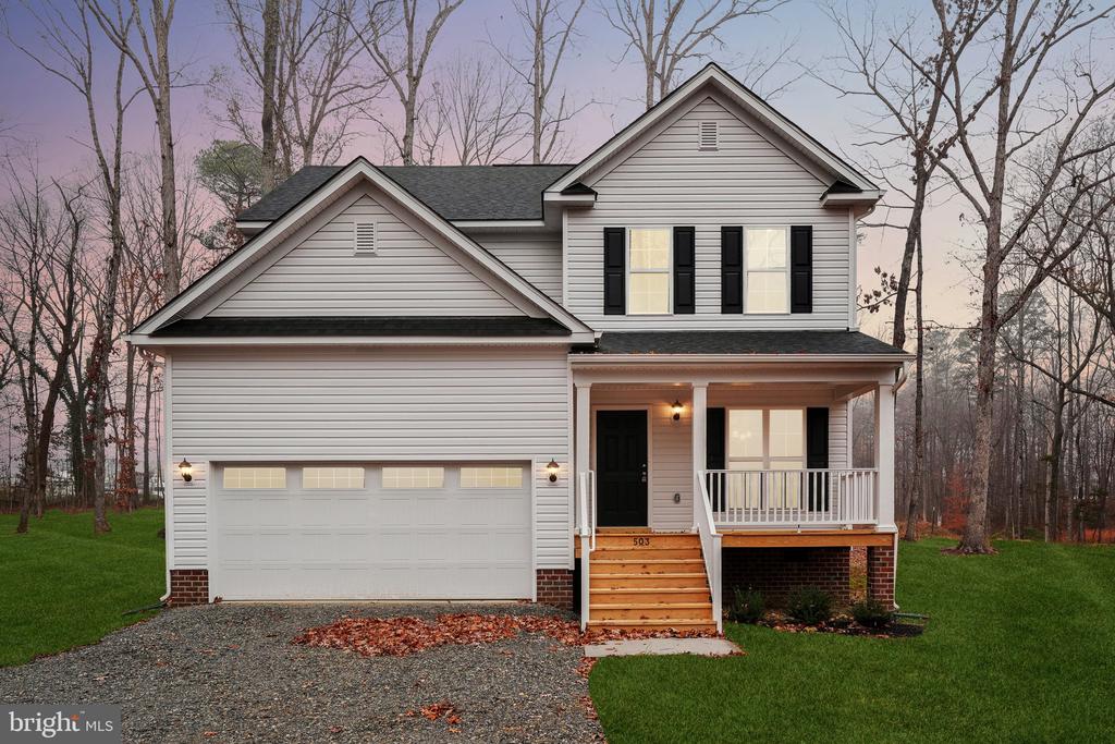 view of front of property featuring a yard, covered porch, and a garage