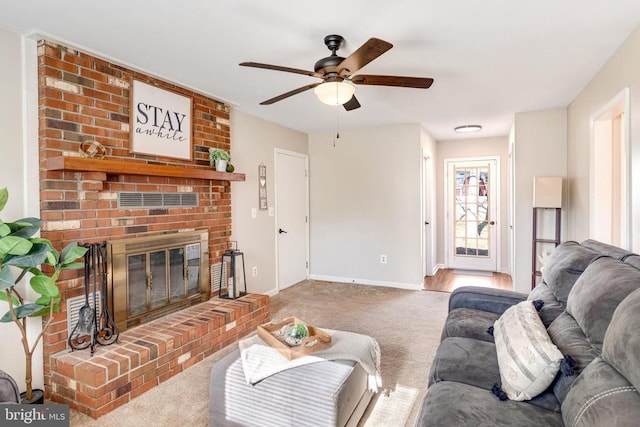 carpeted living room with a fireplace, baseboards, and ceiling fan