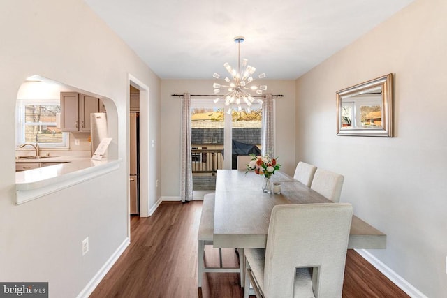 dining space with arched walkways, a notable chandelier, baseboards, and dark wood-style flooring