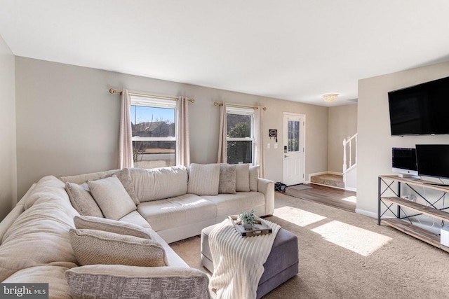 carpeted living area featuring stairs and baseboards