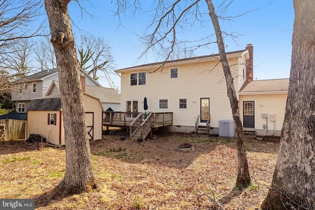 rear view of house with a fire pit, a wooden deck, a chimney, a storage shed, and an outdoor structure