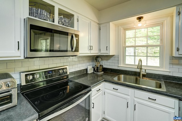 kitchen with a sink, backsplash, stainless steel appliances, and white cabinetry