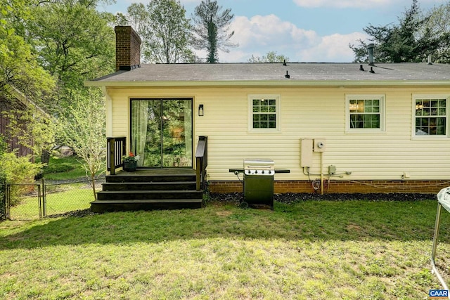 rear view of property with a lawn, fence, and a chimney