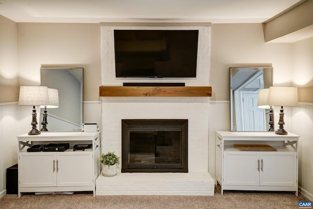 carpeted living room featuring wainscoting and a fireplace