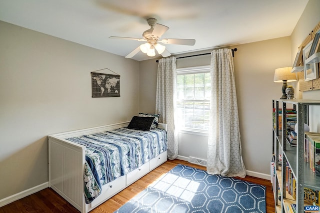 bedroom featuring baseboards, a ceiling fan, wood finished floors, and visible vents