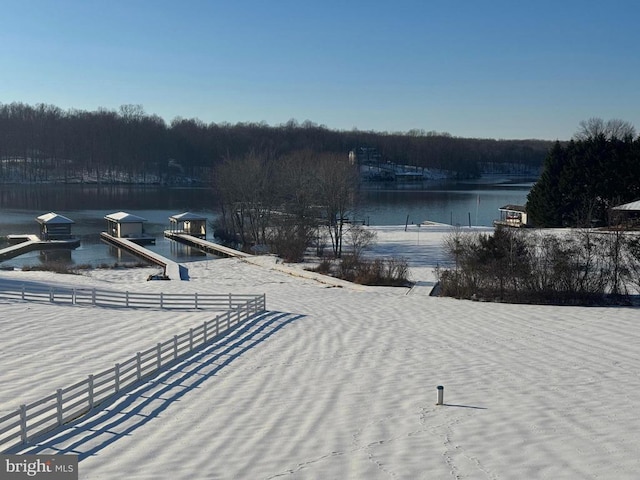 property view of water featuring fence and a wooded view