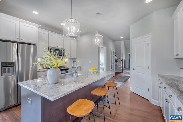 kitchen with a breakfast bar area, stainless steel appliances, a sink, white cabinets, and dark wood-style floors