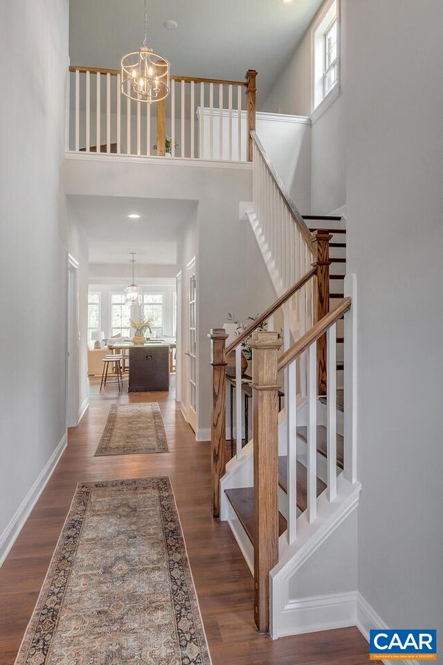 stairway featuring baseboards, a chandelier, and wood finished floors