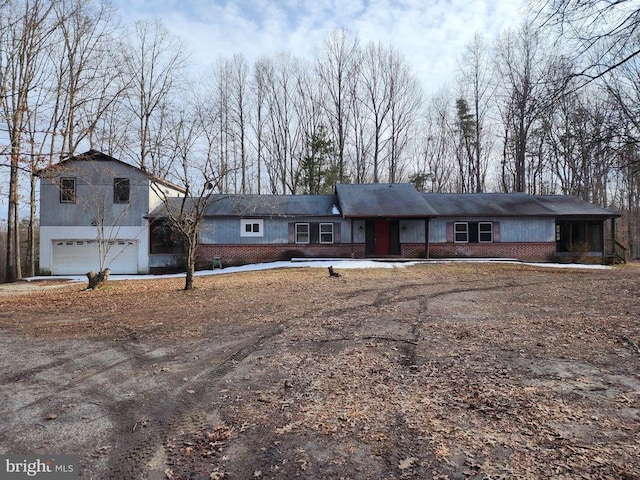 ranch-style home featuring dirt driveway, brick siding, and a garage