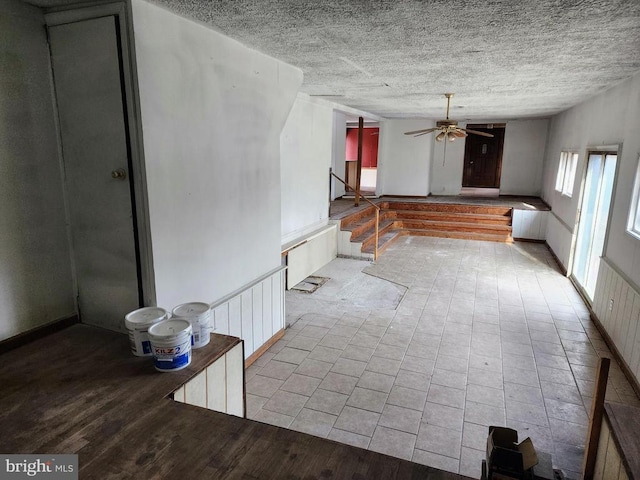 interior space with a ceiling fan, a textured ceiling, wood finished floors, and stairs