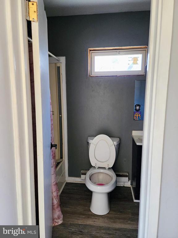 bathroom with shower / bathtub combination, toilet, vanity, wood finished floors, and baseboards