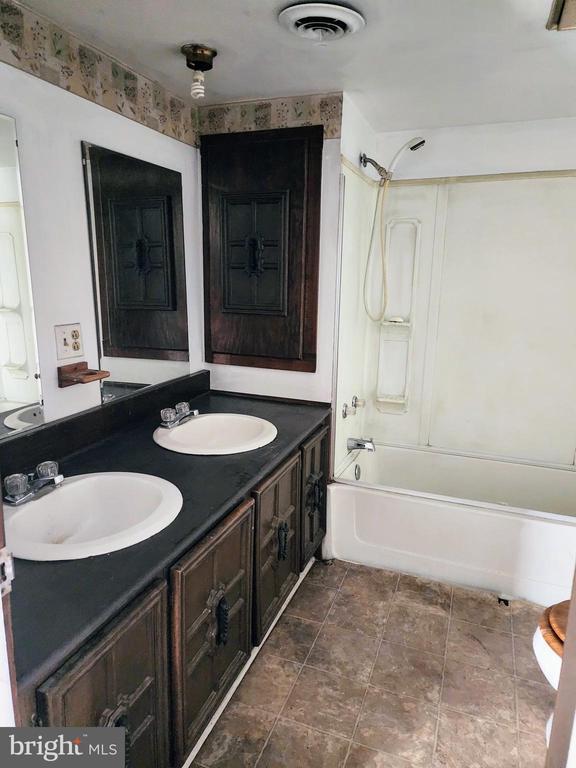 full bath with bathtub / shower combination, double vanity, visible vents, and a sink