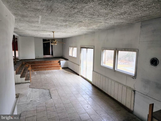 spare room with ceiling fan, stairs, and a textured ceiling