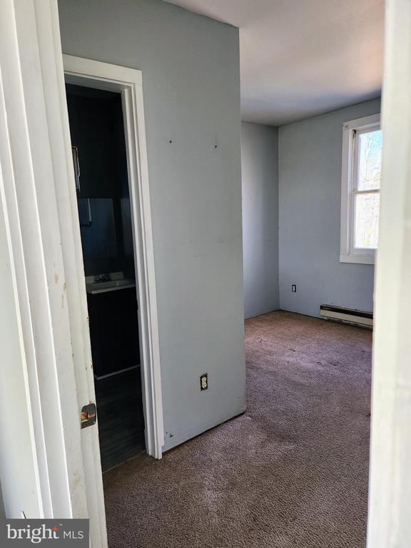 empty room with baseboard heating and carpet