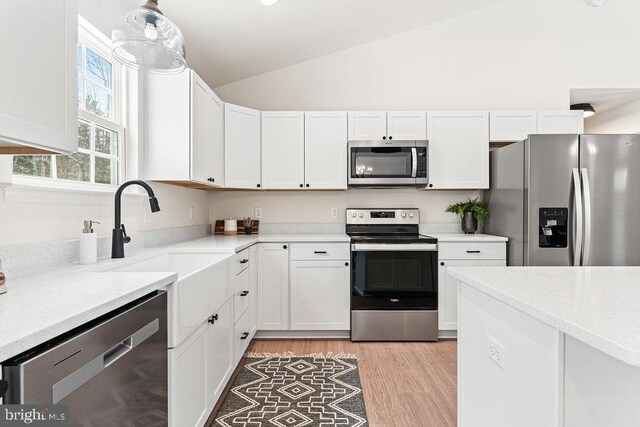 kitchen featuring stainless steel appliances, sink, vaulted ceiling, and white cabinets