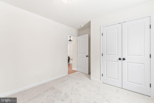 unfurnished bedroom with light carpet and a closet