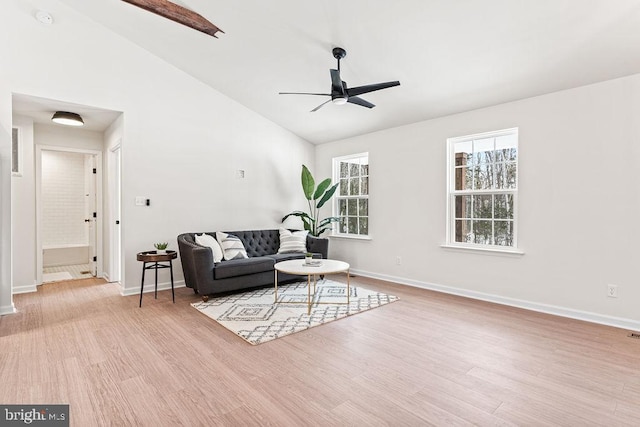 living room with high vaulted ceiling, ceiling fan, and light wood-type flooring