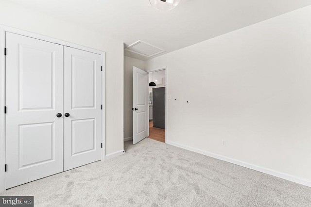 unfurnished bedroom featuring light carpet, a closet, and black fridge