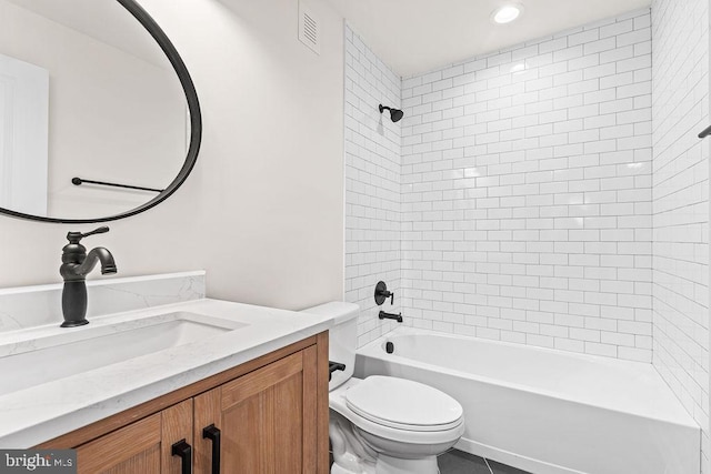 full bathroom featuring vanity, tiled shower / bath, and toilet