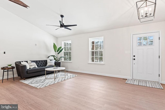 living room featuring ceiling fan with notable chandelier, vaulted ceiling, and light hardwood / wood-style floors