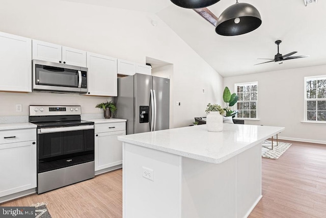 kitchen with stainless steel appliances, a center island, light stone counters, light hardwood / wood-style floors, and white cabinets