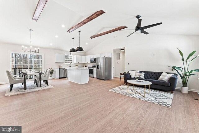 living room featuring sink, ceiling fan with notable chandelier, high vaulted ceiling, and light hardwood / wood-style flooring