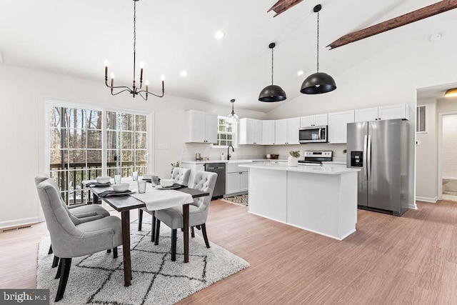 dining space with a notable chandelier, sink, high vaulted ceiling, and light wood-type flooring