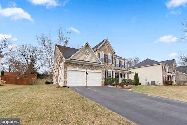 traditional-style home featuring aphalt driveway, cooling unit, a garage, fence, and a front lawn