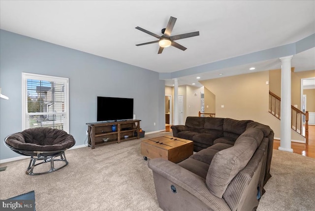 carpeted living room with stairs, decorative columns, baseboards, and ceiling fan