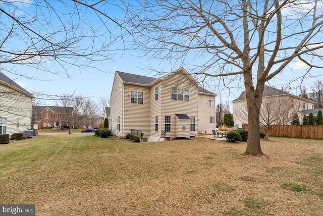 rear view of property featuring central air condition unit, fence, a lawn, and a patio