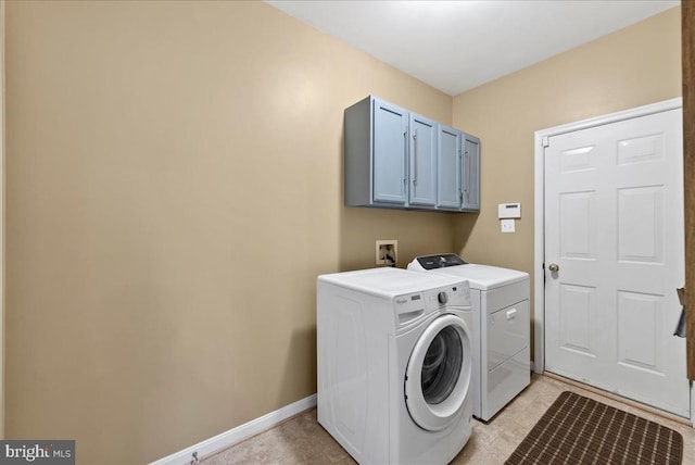 clothes washing area with washer and dryer, cabinet space, and baseboards