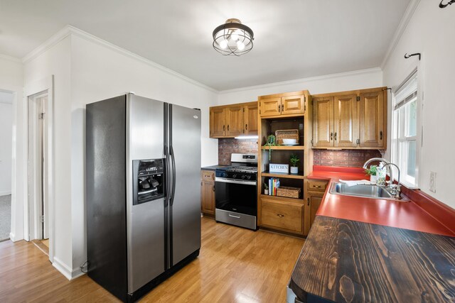 kitchen with sink, crown molding, backsplash, stainless steel appliances, and light hardwood / wood-style floors