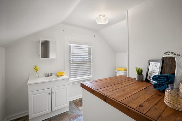 interior space with lofted ceiling, sink, and white cabinets