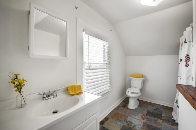 bathroom featuring vanity, lofted ceiling, and toilet