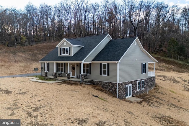 cape cod house featuring covered porch, driveway, and roof with shingles