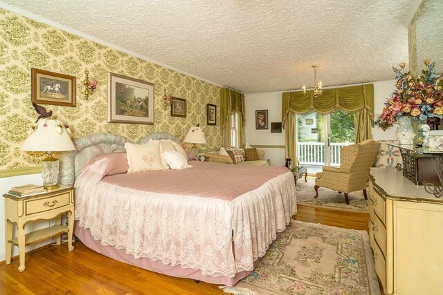 bedroom with crown molding, an inviting chandelier, access to exterior, wood-type flooring, and a textured ceiling