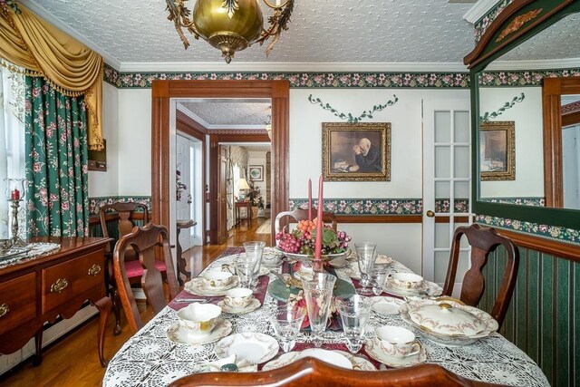 dining room featuring crown molding, hardwood / wood-style floors, and a textured ceiling