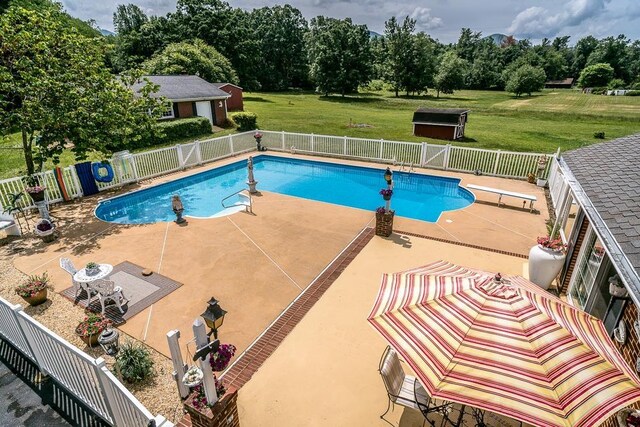 view of pool featuring a diving board, a lawn, and a patio