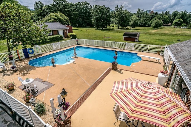 view of pool featuring a diving board, a lawn, and a patio