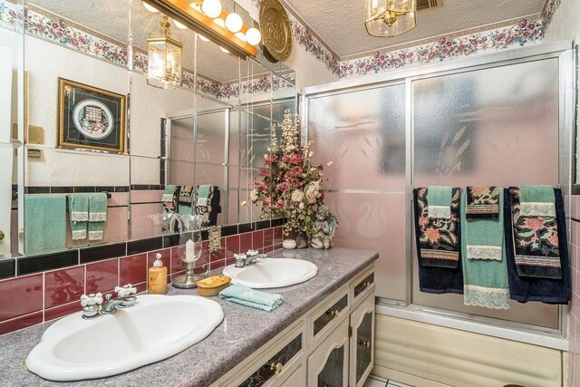 bathroom featuring a textured ceiling, tile walls, vanity, enclosed tub / shower combo, and decorative backsplash