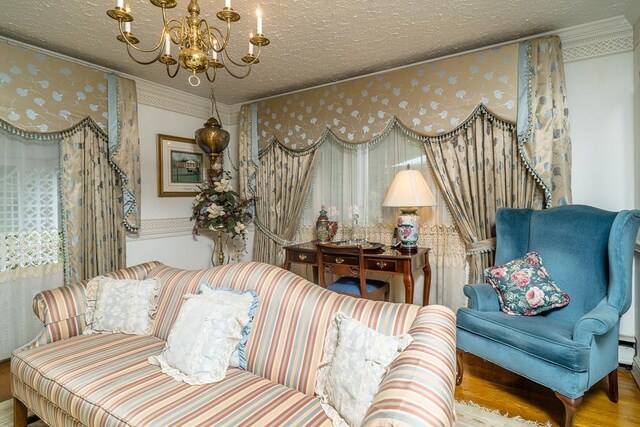 sitting room with ornamental molding, wood-type flooring, a chandelier, and a textured ceiling