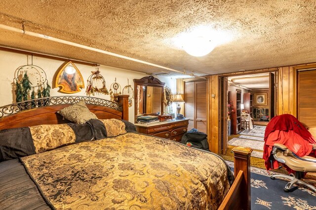 bedroom with multiple closets, wood-type flooring, and a textured ceiling