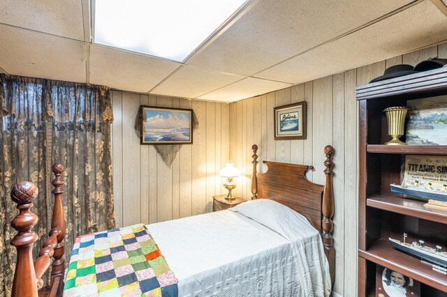 bedroom with a drop ceiling and wooden walls