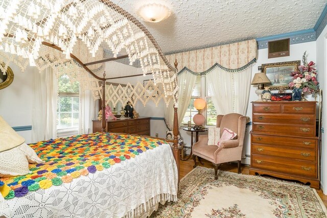 bedroom featuring hardwood / wood-style flooring, ornamental molding, and a textured ceiling