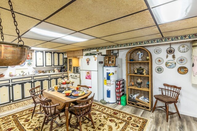 dining space featuring electric water heater, hardwood / wood-style floors, and a drop ceiling