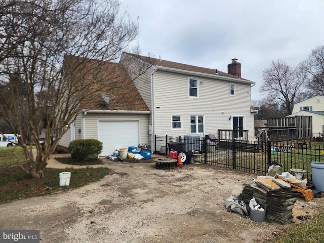 back of property featuring fence, a garage, driveway, and a chimney