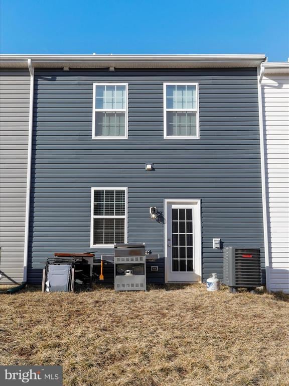 back of property featuring central AC unit and a lawn