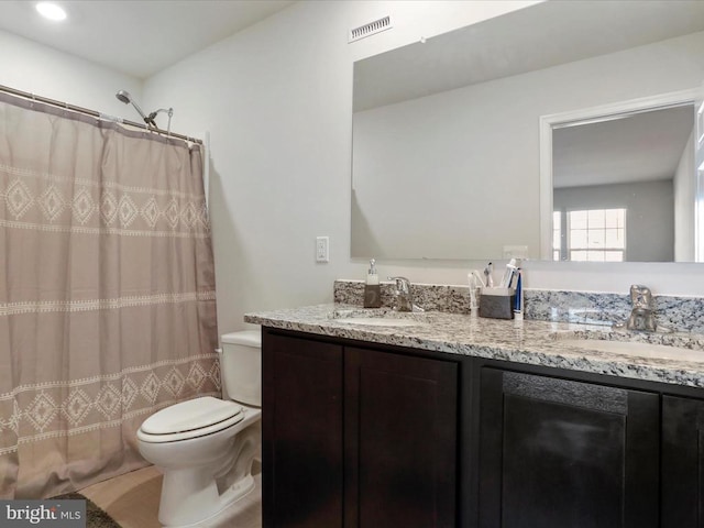 bathroom featuring vanity, toilet, and walk in shower