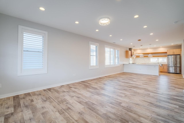 unfurnished living room featuring sink and light hardwood / wood-style floors